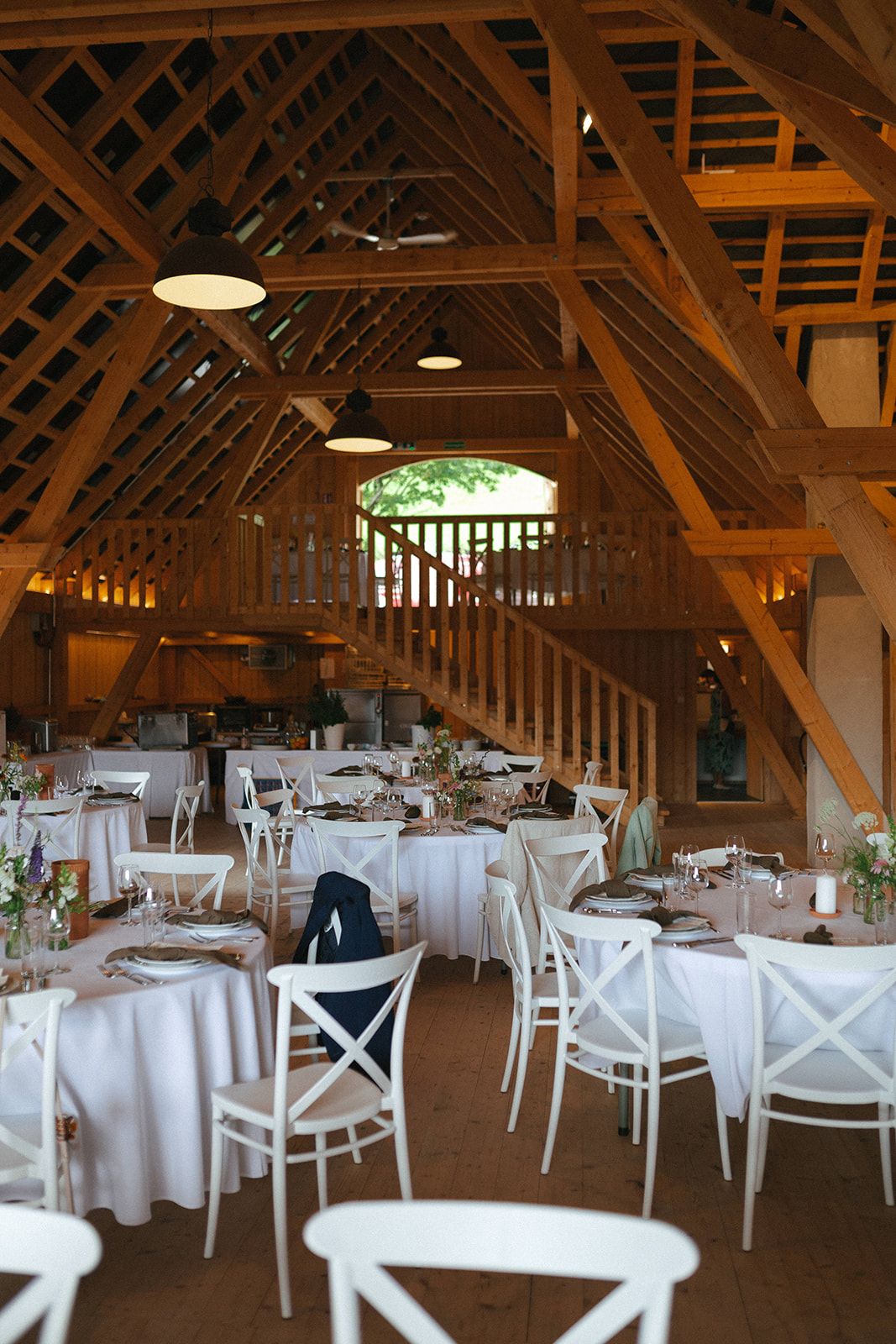 Hochzeit in einem Holzstadl mit runden Tischen und Crossback-Sesseln