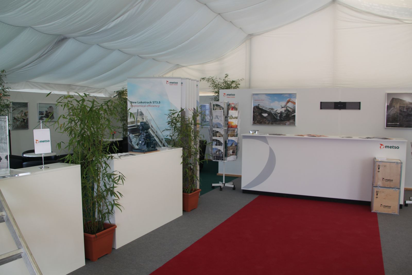Messestand in einem Zelt mit Innenhimmel, Theke, Prospektständer und rotem Teppich